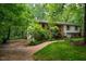Lovely exterior view with driveway, manicured lawn, lush trees, and brick walkway leading to the home at 803 Churchill Dr, Chapel Hill, NC 27517