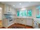 Well-lit kitchen features white cabinets, appliances, and hardwood floors, with ample natural light and counter space at 803 Churchill Dr, Chapel Hill, NC 27517