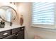 Updated half-bathroom with a modern round mirror, elegant vanity, and plantation shutters at 813 Faulkner Pl, Raleigh, NC 27609