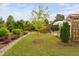 Beautiful landscaped backyard featuring a small tree, a green lawn, and a vine covered pergola with stone patio at 829 Churton Pl, Cary, NC 27518