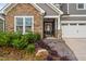 Inviting home exterior with stone accents, a covered porch, a two-car garage, and manicured landscaping at 829 Churton Pl, Cary, NC 27518