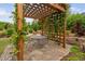 An inviting pergola with climbing plants, stone flooring and an outdoor dining set in a lush backyard setting at 829 Churton Pl, Cary, NC 27518