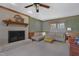 Cozy living room with a painted brick fireplace, ceiling fan, and comfortable seating with wood-trimmed green walls at 8608 Cheerful Ct, Raleigh, NC 27615