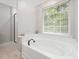 Bright bathroom with a relaxing soaking tub under a large window, complemented by modern fixtures at 8722 Macedonia Lake Dr, Cary, NC 27518