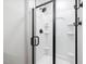 Modern walk-in shower featuring black hardware, white tiles, and convenient storage shelves at 8722 Macedonia Lake Dr, Cary, NC 27518