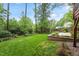 Backyard featuring a lush green lawn with manicured stone planter and a wooden deck at 912 Salem Woods Dr, Raleigh, NC 27615