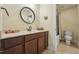 Bathroom featuring dark wood vanity, round mirror, and a shower-tub combination with neutral wall tiling at 1009 Blue Larkspur Ave, Wake Forest, NC 27587
