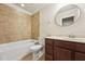 Well-lit bathroom featuring a tub-shower combo with neutral tile, a dark wood vanity, and a round mirror at 1009 Blue Larkspur Ave, Wake Forest, NC 27587