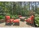 Outdoor patio with a fire pit and orange cushioned seating surrounded by landscaping at 1009 Blue Larkspur Ave, Wake Forest, NC 27587