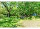 Large backyard with mature trees, a swing set, and storage shed at 110 E Church St, Creedmoor, NC 27522