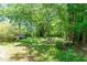 Lush backyard with mature trees, a swing set, shed, and plenty of greenery at 110 E Church St, Creedmoor, NC 27522