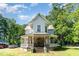 Charming two-story home featuring a classic front porch and mature trees on a sunny day at 110 E Church St, Creedmoor, NC 27522