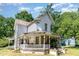 Angle view of a two-story home with a charming front porch surrounded by mature trees at 110 E Church St, Creedmoor, NC 27522