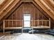 An unfinished attic space with wooden beams, storage shelving and a window for natural light at 1206 Chalk Maple Dr, Cary, NC 27519