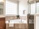 Bright bathroom featuring a soaking tub, large window, and tiled surround at 1206 Chalk Maple Dr, Cary, NC 27519