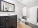 Bathroom with dark cabinets, neutral tile floor, shower over tub, and framed mirror at 12424 Beauvoir St, Raleigh, NC 27614