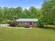 Brick single-story home with a well-manicured lawn, mature trees, and a charming front entrance with landscaping at 1514 Lawrence Rd, Creedmoor, NC 27522