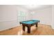 Well-lit game room with a pool table, hardwood floors, and plantation shutters for natural light control at 1514 Lawrence Rd, Creedmoor, NC 27522