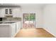 Updated kitchen with white cabinetry, hardwood floors, stone backsplash, and a sliding door to the outdoor pool area at 1514 Lawrence Rd, Creedmoor, NC 27522