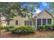 Tan home with a screened in porch, surrounded by lush landscaping and mature trees at 1608 Heritage Links Dr, Wake Forest, NC 27587