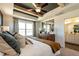 This primary bedroom features a tray ceiling with exposed beams, a ceiling fan, and a large window with a view at 18 Relaxing Way, Pittsboro, NC 27312