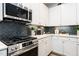 Close up of kitchen with white cabinets, stainless steel stove, herringbone backsplash, and quartz countertops at 18 Relaxing Way, Pittsboro, NC 27312