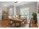 Dining room with a rustic wooden table, neutral chairs, and a large window offering natural light at 2010 Silky Dogwood Trl, Apex, NC 27502