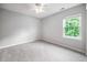This bedroom has neutral colors and carpeted floors with a view of the backyard through the window at 2018 Grassy Banks Dr, Raleigh, NC 27610