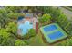Aerial view showcasing community pool and tennis courts nestled in a lush green landscape near a highway at 203 Witheridge Ct, Apex, NC 27502