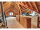Unfinished attic space with plywood flooring, wooden beams and rafters, and a window at 203 Witheridge Ct, Apex, NC 27502