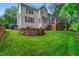 Backyard view featuring a stone fire pit, manicured lawn, and porch and deck on the rear of the home at 203 Witheridge Ct, Apex, NC 27502