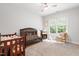 Light-filled Bedroom with a dark wood crib, neutral carpet, a ceiling fan, and a window overlooking lush greenery at 203 Witheridge Ct, Apex, NC 27502