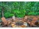 Outdoor stone firepit with Adirondack chairs on a paver patio, surrounded by green trees at 203 Witheridge Ct, Apex, NC 27502