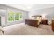 Spacious main bedroom features a bed facing a large window, light colored walls and carpet at 203 Witheridge Ct, Apex, NC 27502
