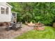 Back patio with pavers features an outdoor dining table and stone-enclosed fire pit surrounded by lush landscaping at 203 Witheridge Ct, Apex, NC 27502