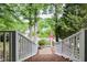 Pathway with white railings and brick stairs leading to a charming home with trees and an American flag at 204 Muirfield Ln, Clayton, NC 27527