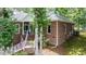 A charming red brick home with a white-railed porch, green plants, and American flag at 204 Muirfield Ln, Clayton, NC 27527