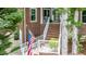 Beautiful red brick home featuring a white-railed porch, green foliage and an American flag at 204 Muirfield Ln, Clayton, NC 27527
