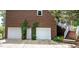 This exterior shot features a two car garage with brick walls and plants surrounding at 204 Muirfield Ln, Clayton, NC 27527