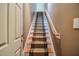 Carpeted stairway featuring wooden handrail leads to the upper level in this home at 204 Muirfield Ln, Clayton, NC 27527