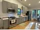 Well-lit kitchen featuring stainless steel appliances, gray cabinets, and hardwood floors at 306 Roebling Ln, Cary, NC 27513