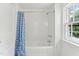 Clean and bright bathroom features white tile, a shower-tub combo with a blue patterned curtain, and a window at 3210 Merriman Ave, Raleigh, NC 27607