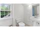 Bright bathroom features white tile, a pedestal sink, a window overlooking the lush trees, and a nearby toilet at 3210 Merriman Ave, Raleigh, NC 27607