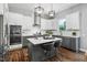Contemporary kitchen with stainless appliances, gray cabinets, island with bar stools, and tiled backsplash at 329 Royal Delta Dr, Cary, NC 27519