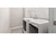 Bright laundry area equipped with modern side-by-side washing machine and dryer on tile floor with hanging shelf at 329 Royal Delta Dr, Cary, NC 27519