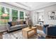 Bright living room featuring large windows, a stylish gray sofa, and a wooden coffee table at 329 Royal Delta Dr, Cary, NC 27519
