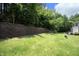 A grassy backyard has a retaining wall and mature trees at 365 Red Elm Dr, Durham, NC 27713