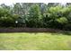 Grassy backyard has a retaining wall and mature trees at the property line at 365 Red Elm Dr, Durham, NC 27713