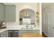 A modern kitchen sink with stainless steel appliances and light green cabinetry is open to the living room at 365 Red Elm Dr, Durham, NC 27713