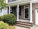 Inviting front entrance featuring white columns, brick detailing, a glass door, and a manicured shrub for enhanced curb appeal at 437 Henmore Brook Dr Dr, Cary, NC 27519